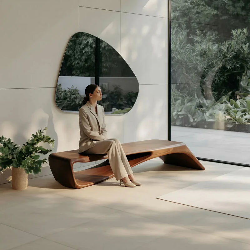 Woman in beige suit sitting on modern wooden bench in minimalist room with large window and greenery