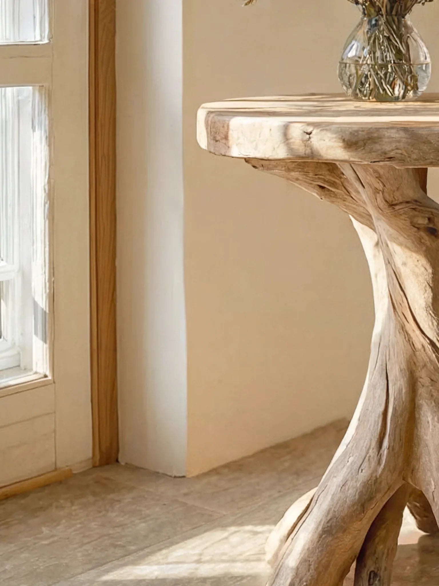 Close-up of a rustic live edge driftwood table with natural wood grain in sunlight.