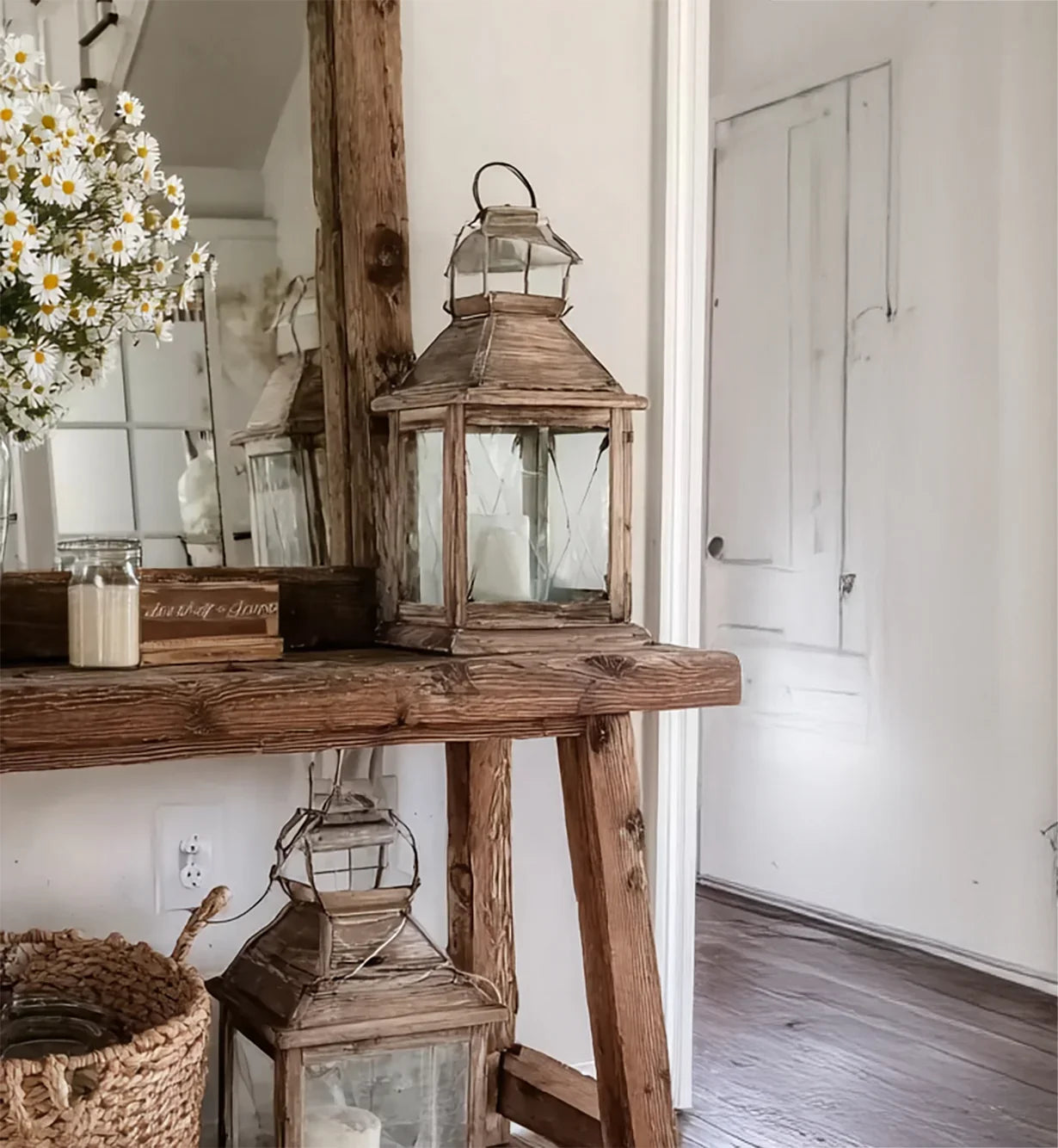Rustic wooden table with decorative lanterns, daisies in vase, and vintage mirror in cozy room