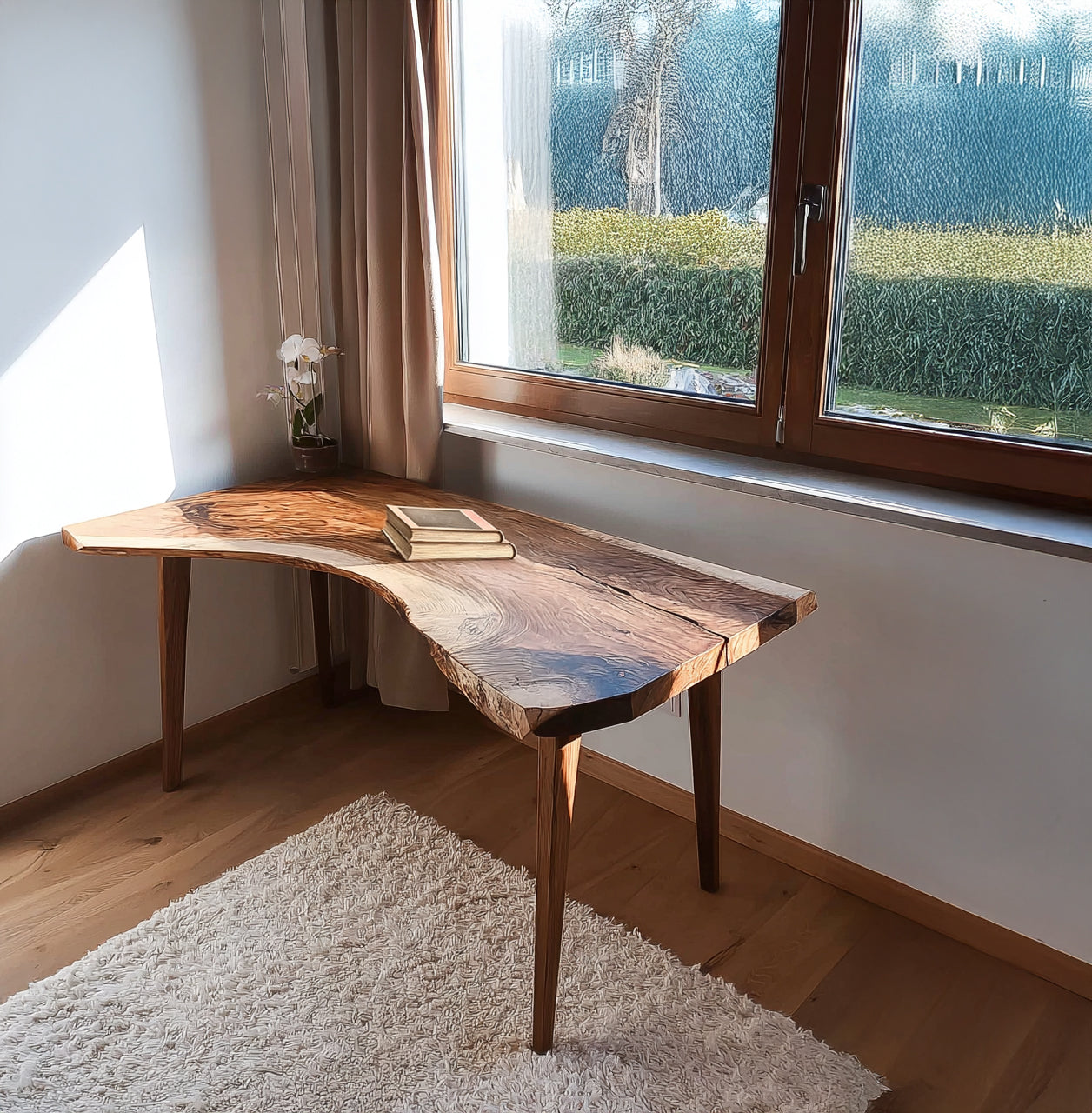 Live edge wooden desk by window with stacked books and small potted orchid in cozy room