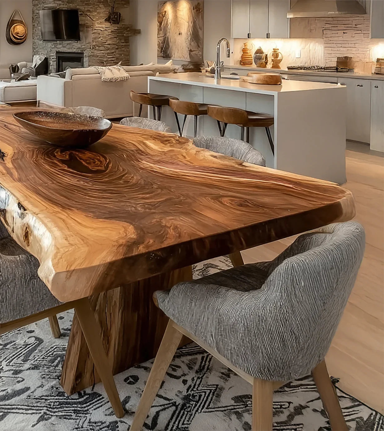 Modern dining area with a live edge wooden table, textured gray chairs, and an open kitchen in the background