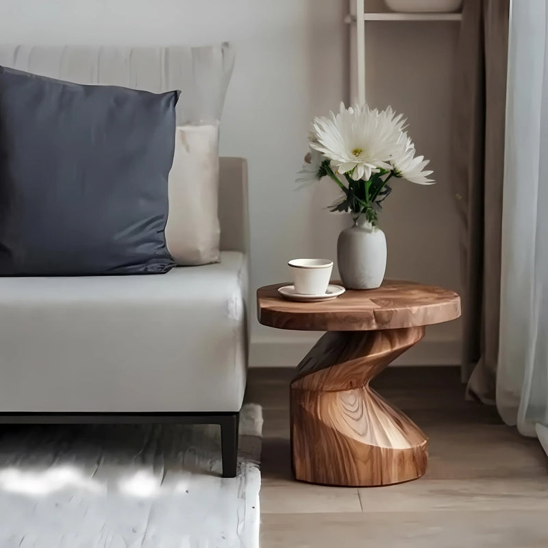 Modern living room with white sofa, dark pillow, wooden twisted side table, white vase with flowers, and coffee cup
