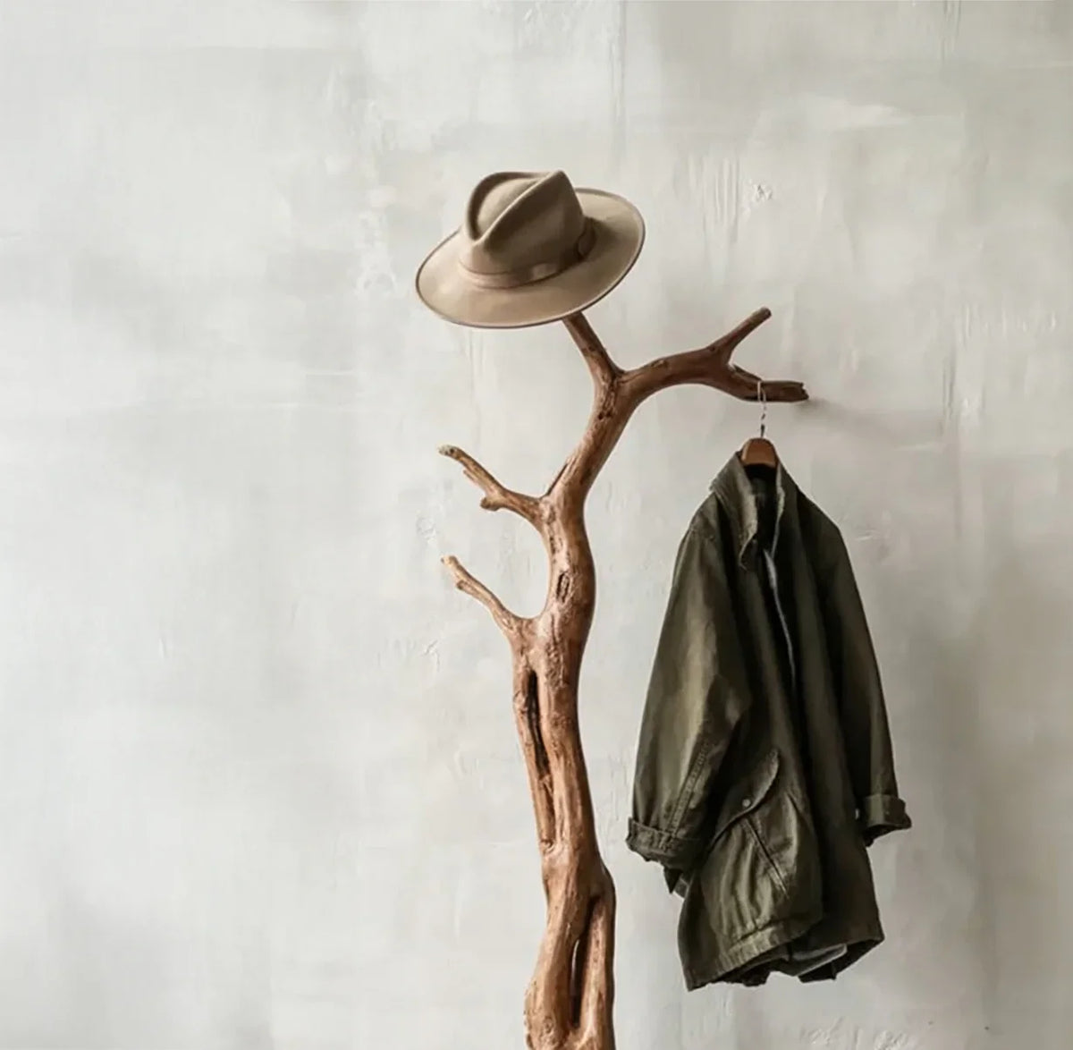 Live edge solid wood coat rack with jacket and hat against a light wall