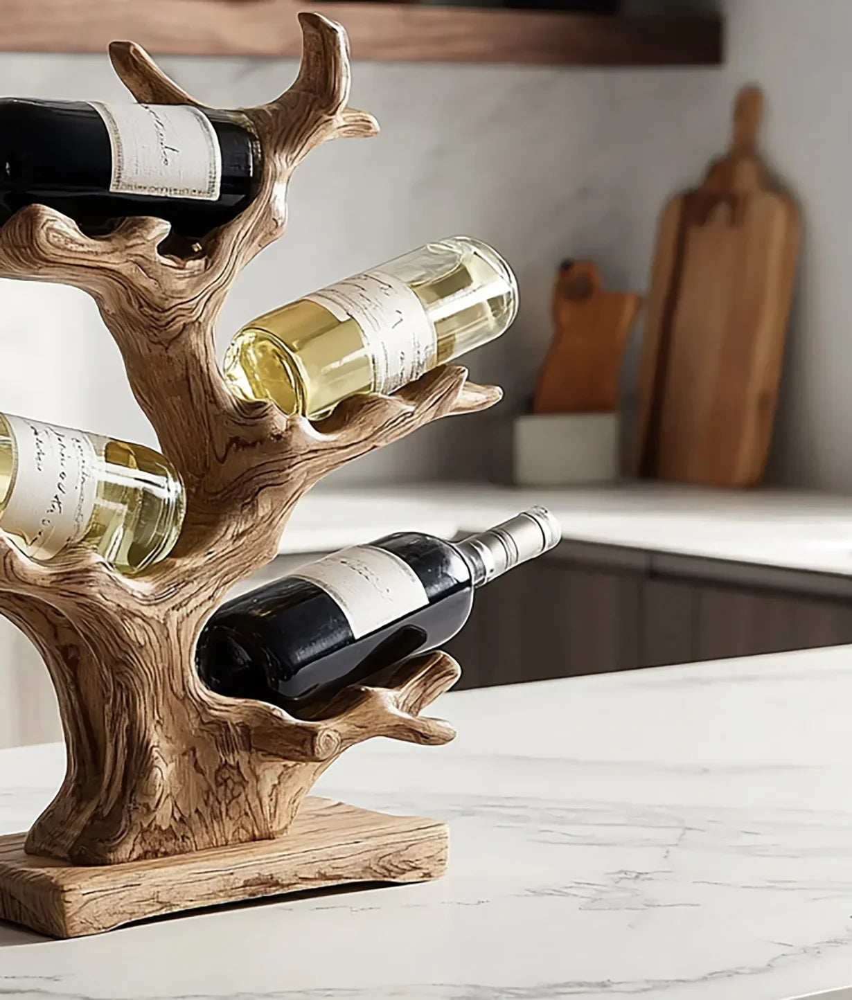 Wooden tree-shaped wine rack holding three bottles of red and white wine on marble kitchen countertop