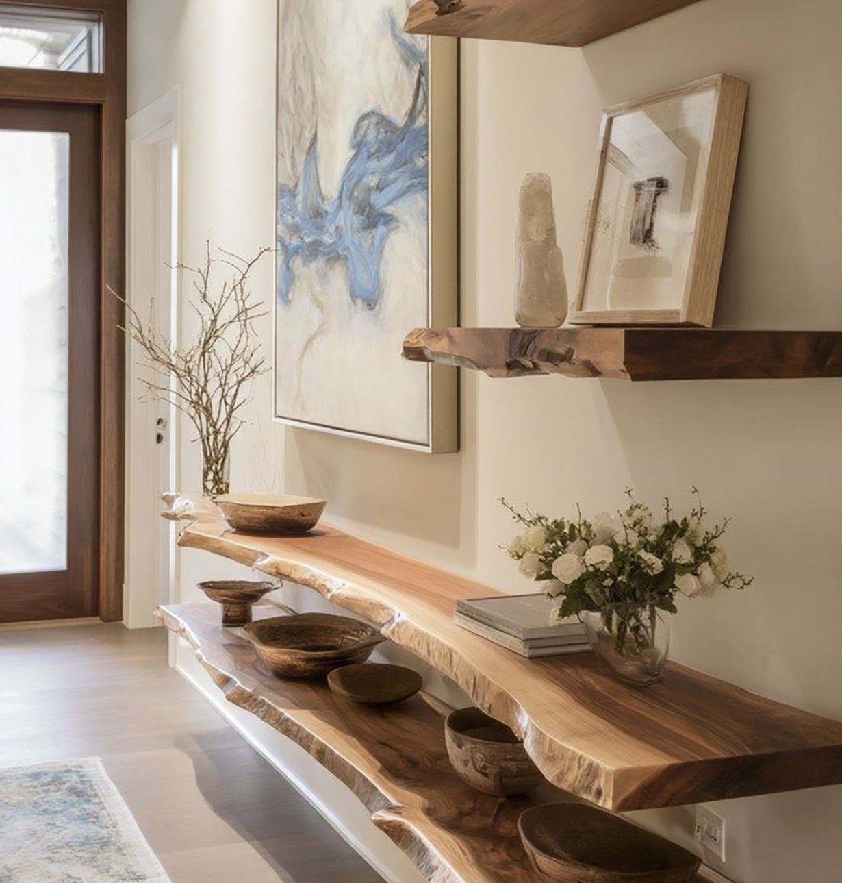 Modern entryway with live edge wooden shelves holding decor, vases, books, and flowers beneath abstract art