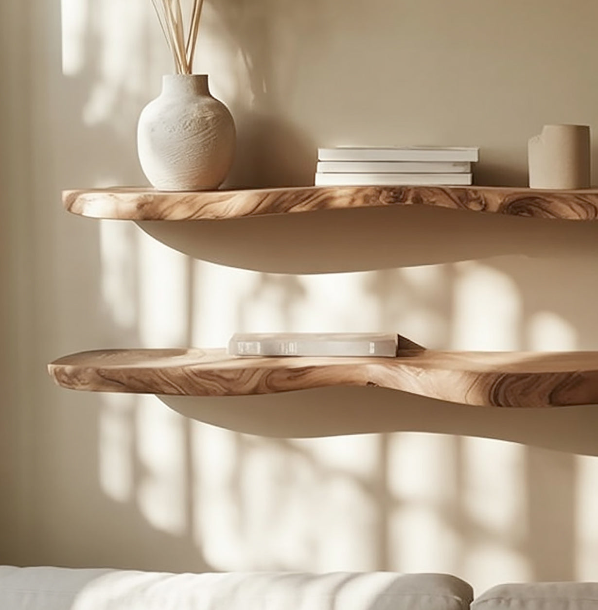 Two live edge solid wood floating shelves on a beige wall, styled with books and ceramics.
