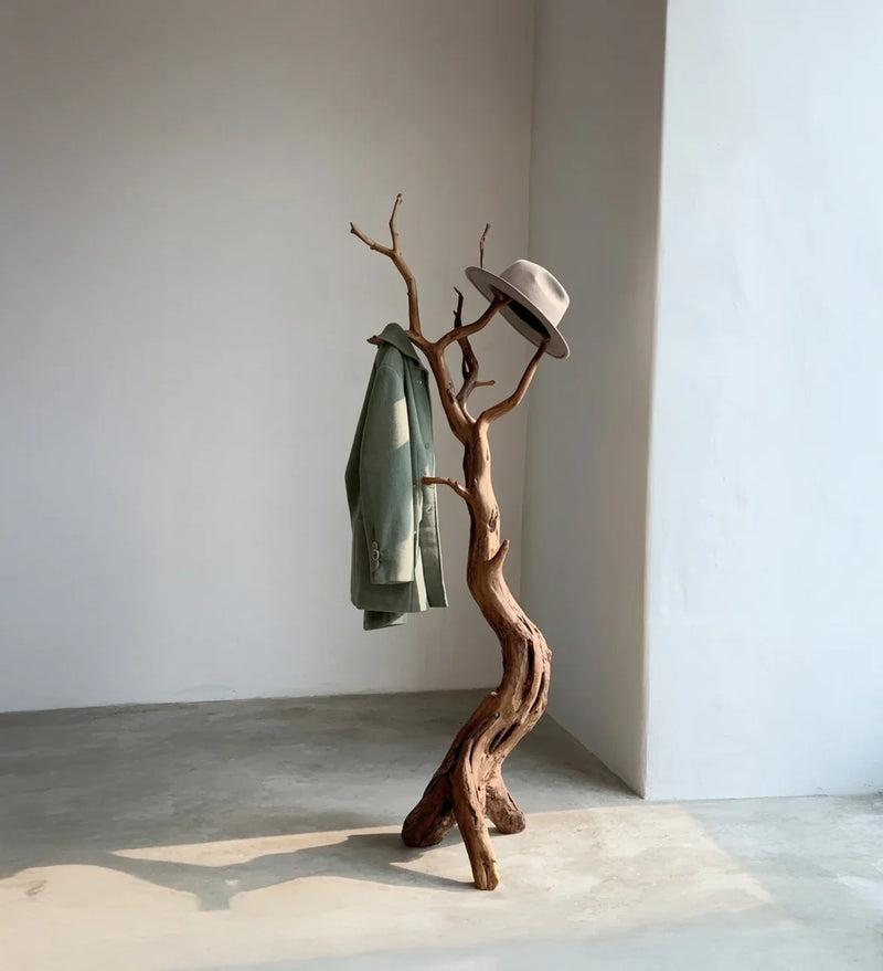 Live edge solid wood coat rack shaped like a tree, holding a green coat and a hat