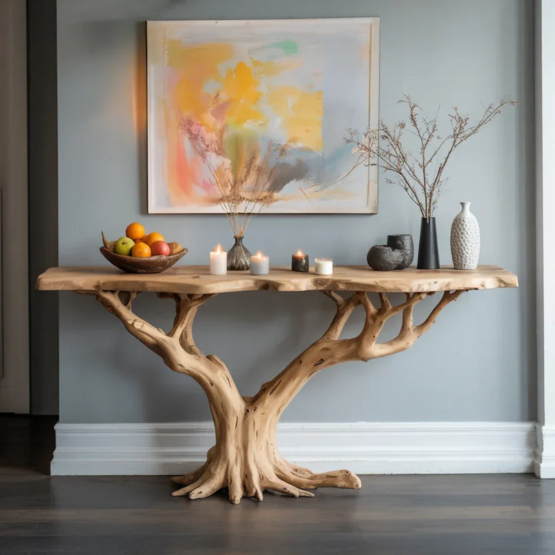 Live edge wood console table with tree-shaped base, decorated with vases, candles, and fruit bowl