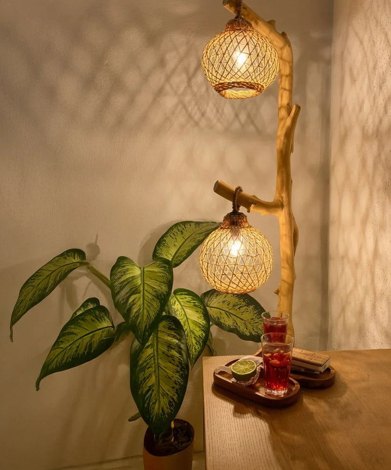 Cozy corner with rattan pendant lamp, potted green plant, and drinks on wooden table
