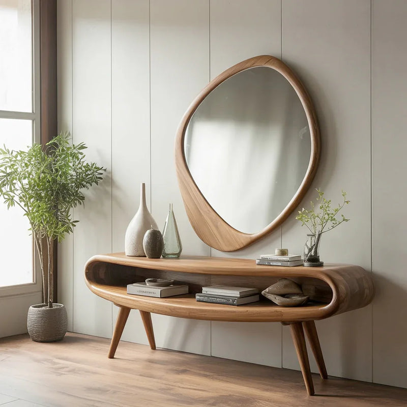 Modern wooden console table with decorative vases and books, paired with an organic-shaped wooden mirror