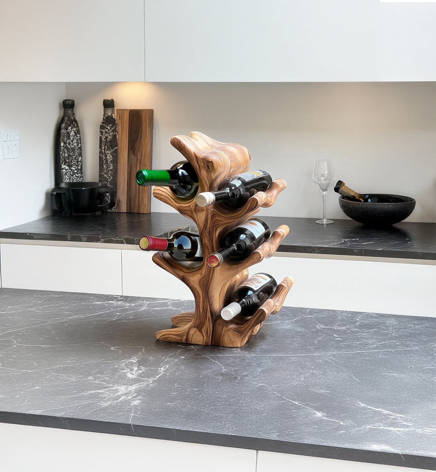 Modern kitchen countertop with wooden tree-shaped wine rack holding six bottles of wine