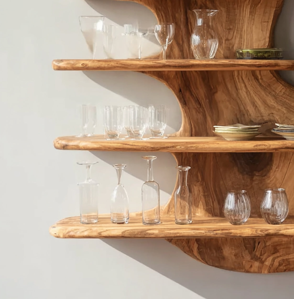 Rustic wooden wall shelves holding various clear glassware and small ceramic bowls