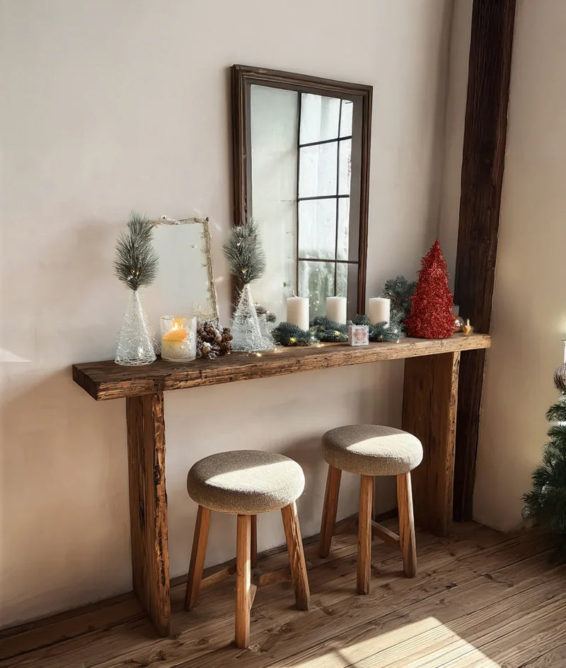Solid wood console table with two stools, holiday decor, candles, and a mirror in a cozy room.