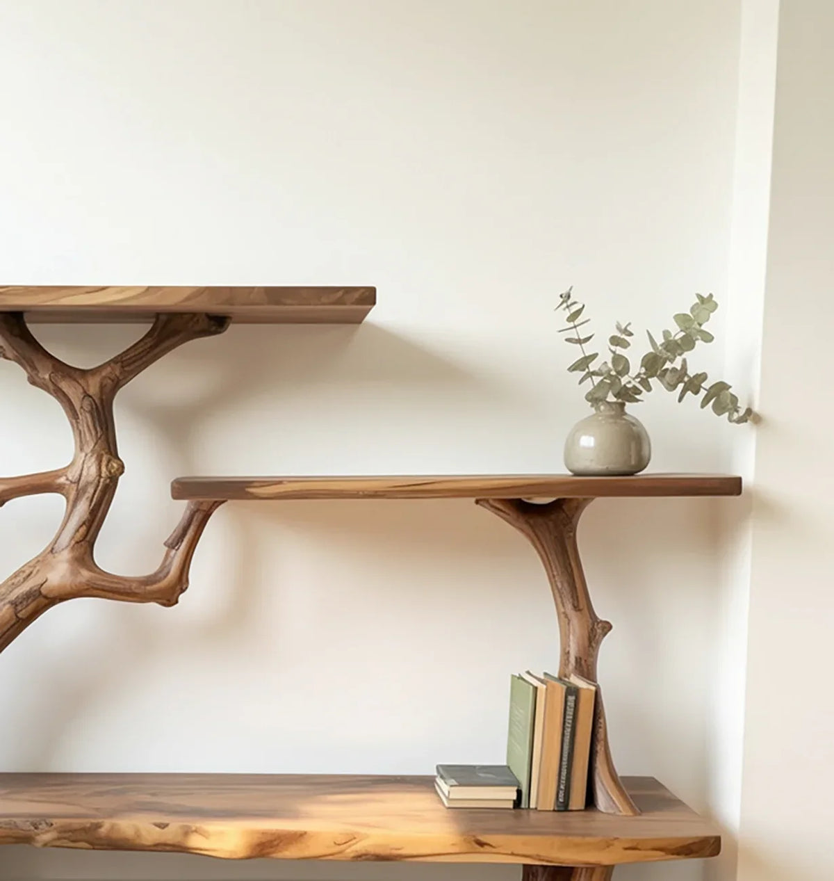 Wooden wall-mounted shelves with natural branch-style supports, decorated with books and a vase with eucalyptus