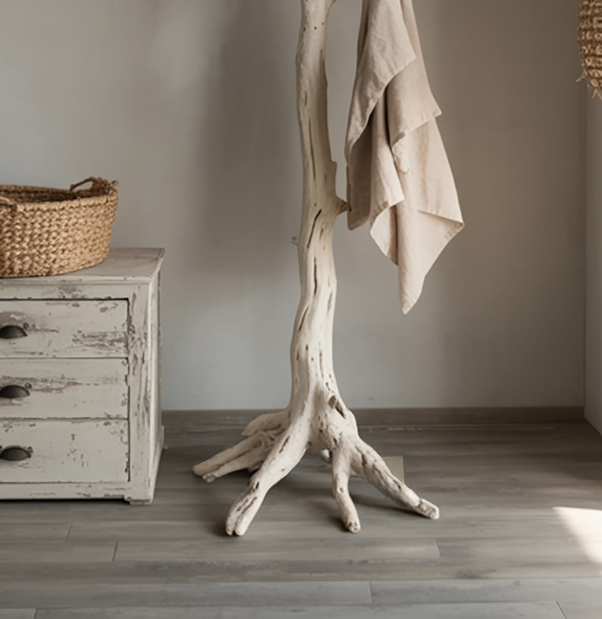 Rustic whitewashed wooden cabinet with woven basket and natural driftwood stand holding beige linen cloth