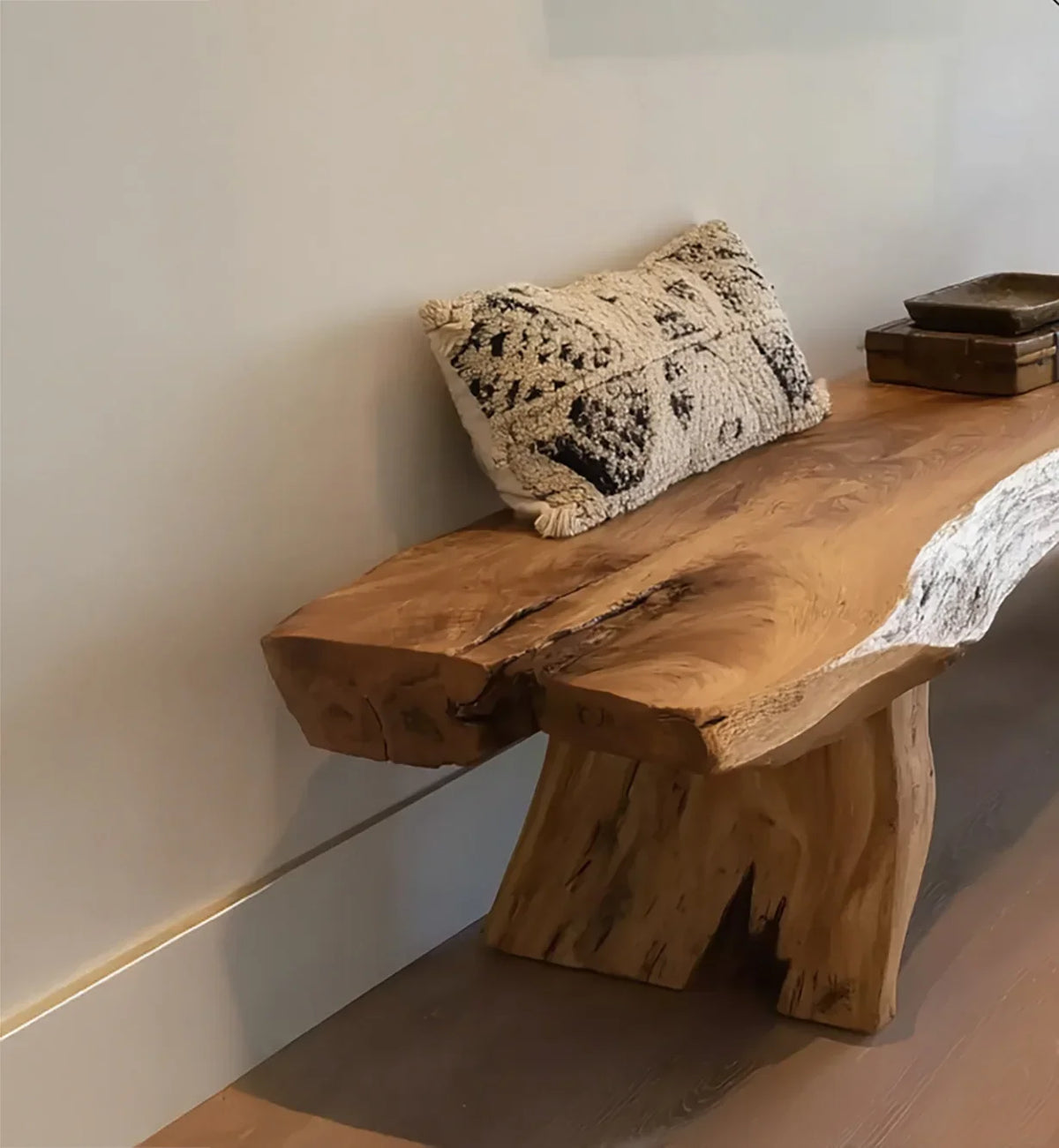 Rustic live edge wooden bench with textured decorative pillow and wooden bowls on hardwood floor