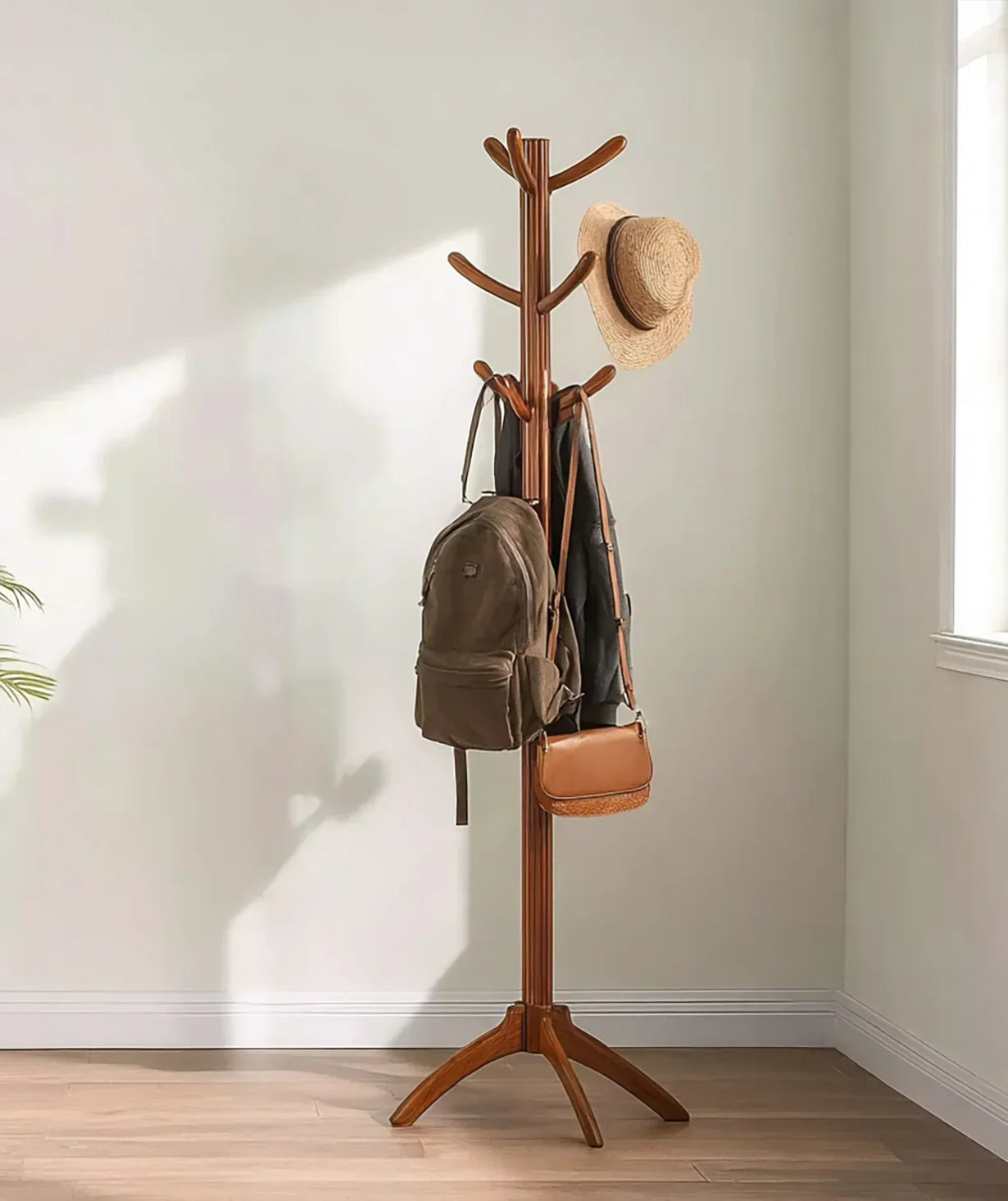 Wooden coat rack with hat, brown backpack, and purse in bright minimalist room