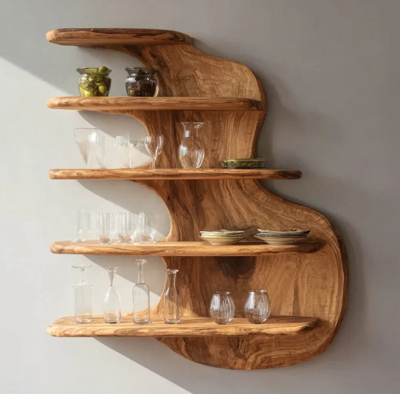 Curved natural wood wall shelves holding glassware, jars, and stacked ceramic plates in soft light