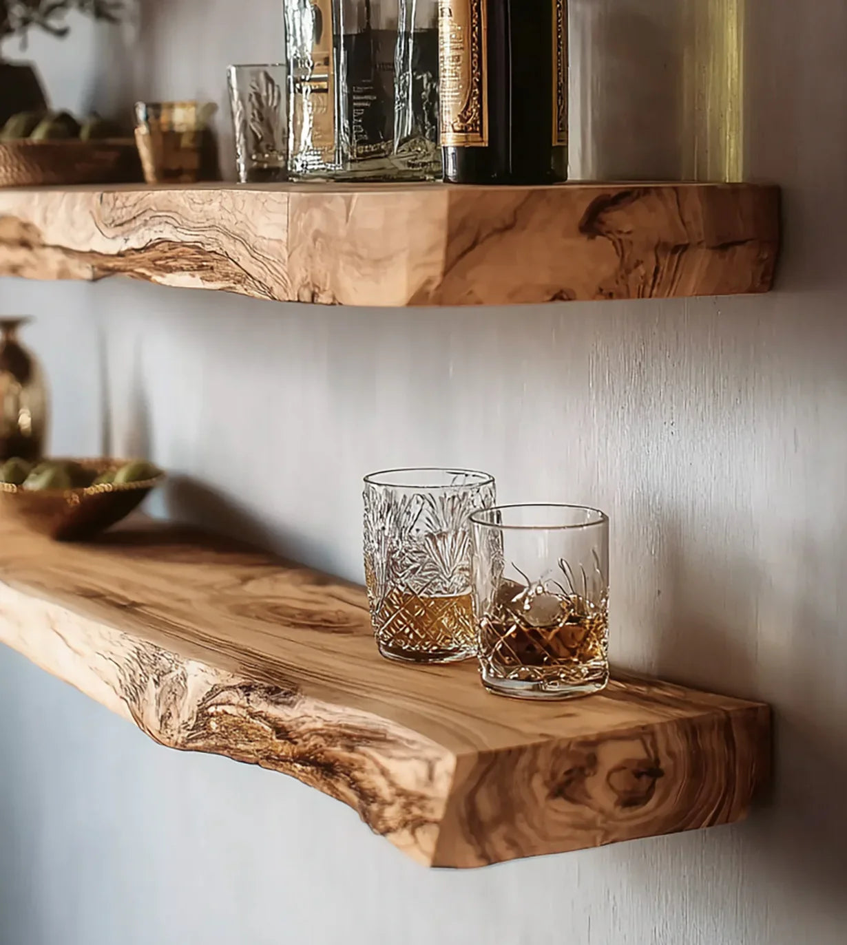 Two crystal glasses with whiskey on a natural live edge wood floating shelf against a light wall