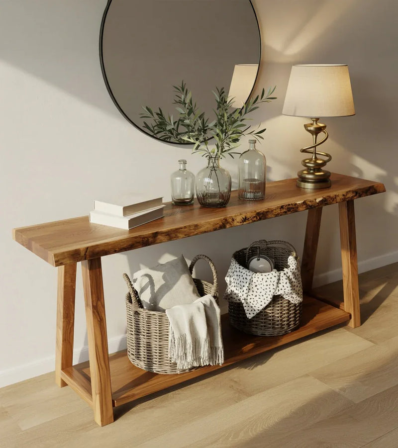 Wooden console table with wicker baskets, decorative glass bottles, greenery, table lamp, and round mirror on wall