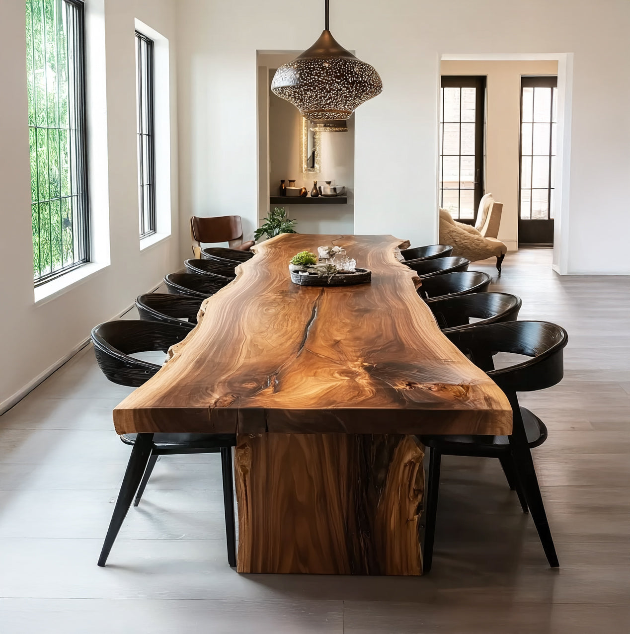 Modern dining room with large live edge wooden table and black chairs under decorative pendant light
