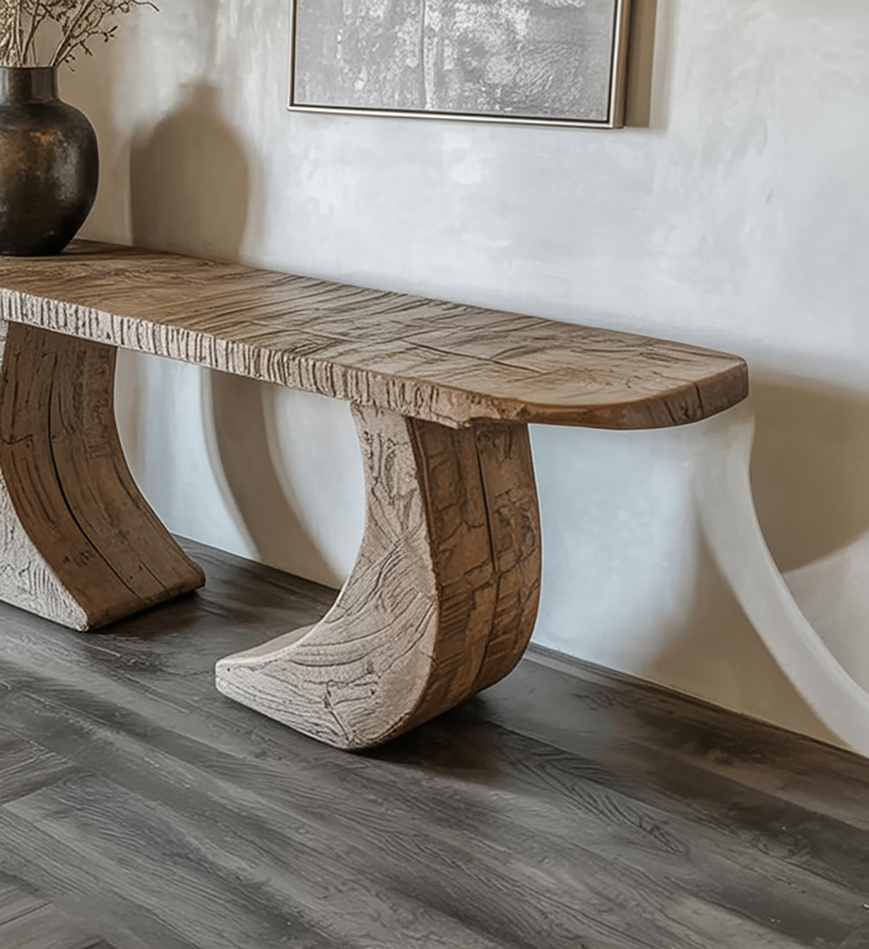 Modern wooden bench with curved legs on gray wood floor against beige wall with artwork and vase