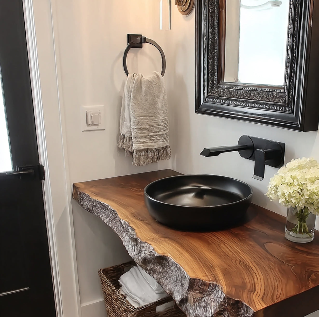 Modern bathroom with live edge wood vanity, black vessel sink, matte black faucet, and rustic mirror