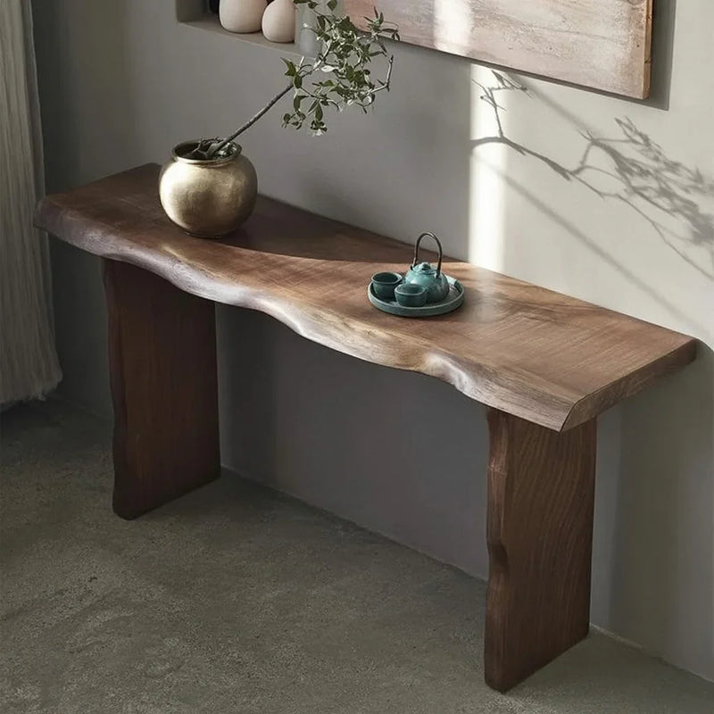 Live edge solid wood console table against wall with decorative vase and ceramic set