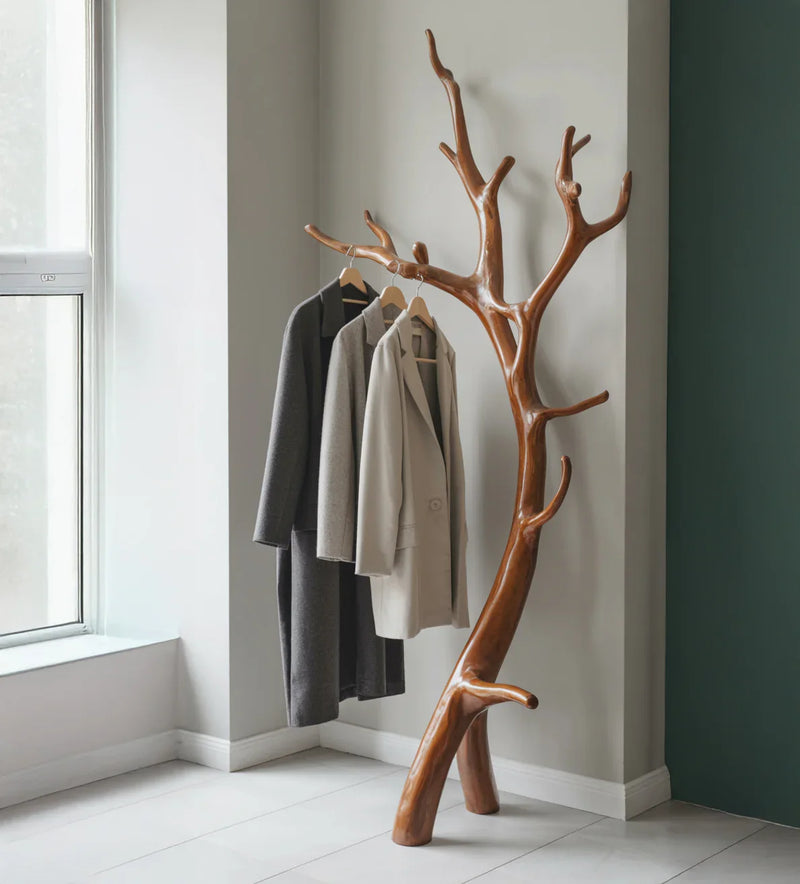 Solid wood tree branch coat rack holding jackets in a modern entryway