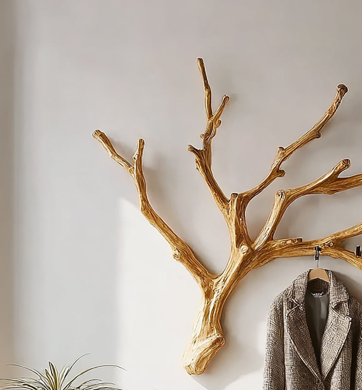 gold tree branch wall hook with a checkered coat hanging in a modern room