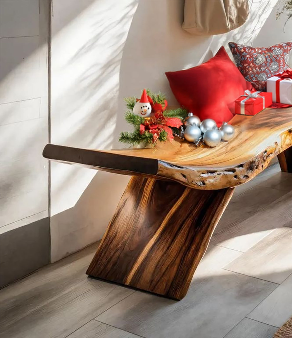 Live edge wooden bench with Christmas decor, red pillows, silver ornaments, and wrapped gifts