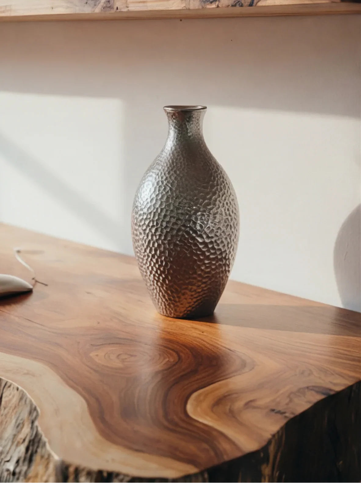 Textured metal vase on a live edge solid wood table with natural grain pattern