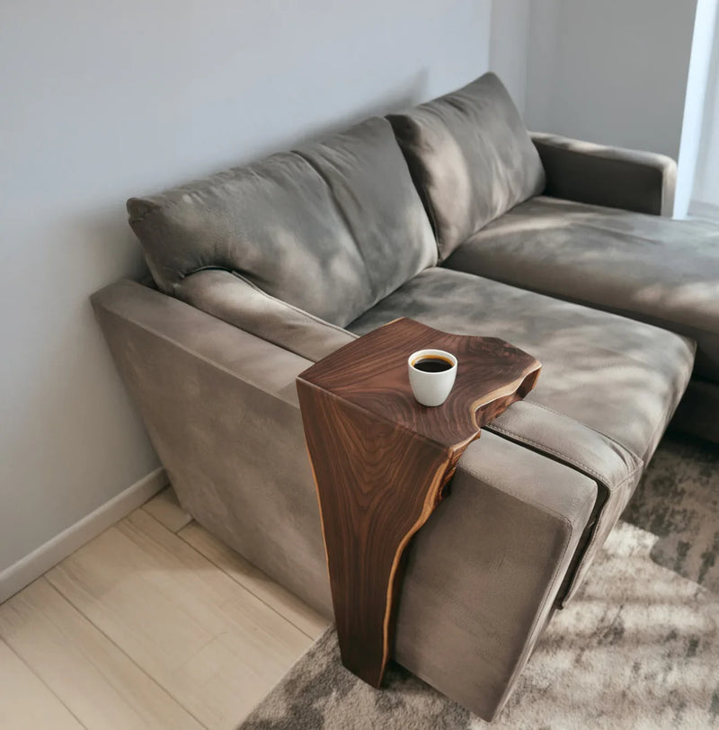 Live edge solid wood sofa arm table holding a coffee cup in a modern living room