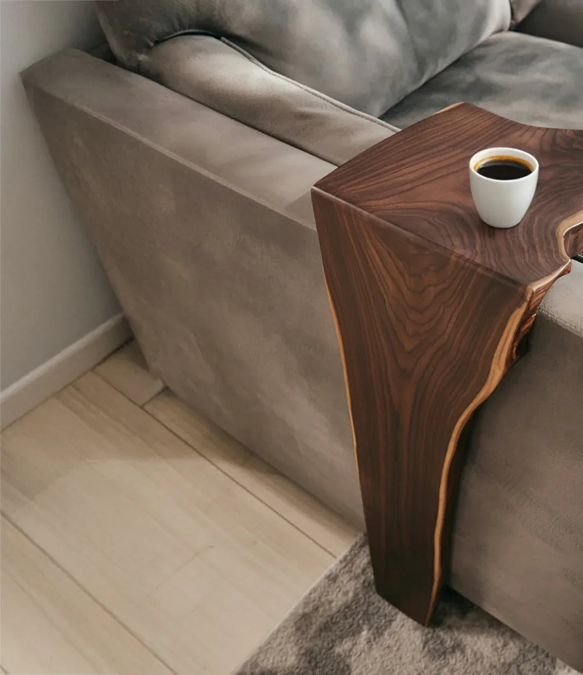 Live edge solid wood sofa arm table holding a cup of coffee in a modern living room