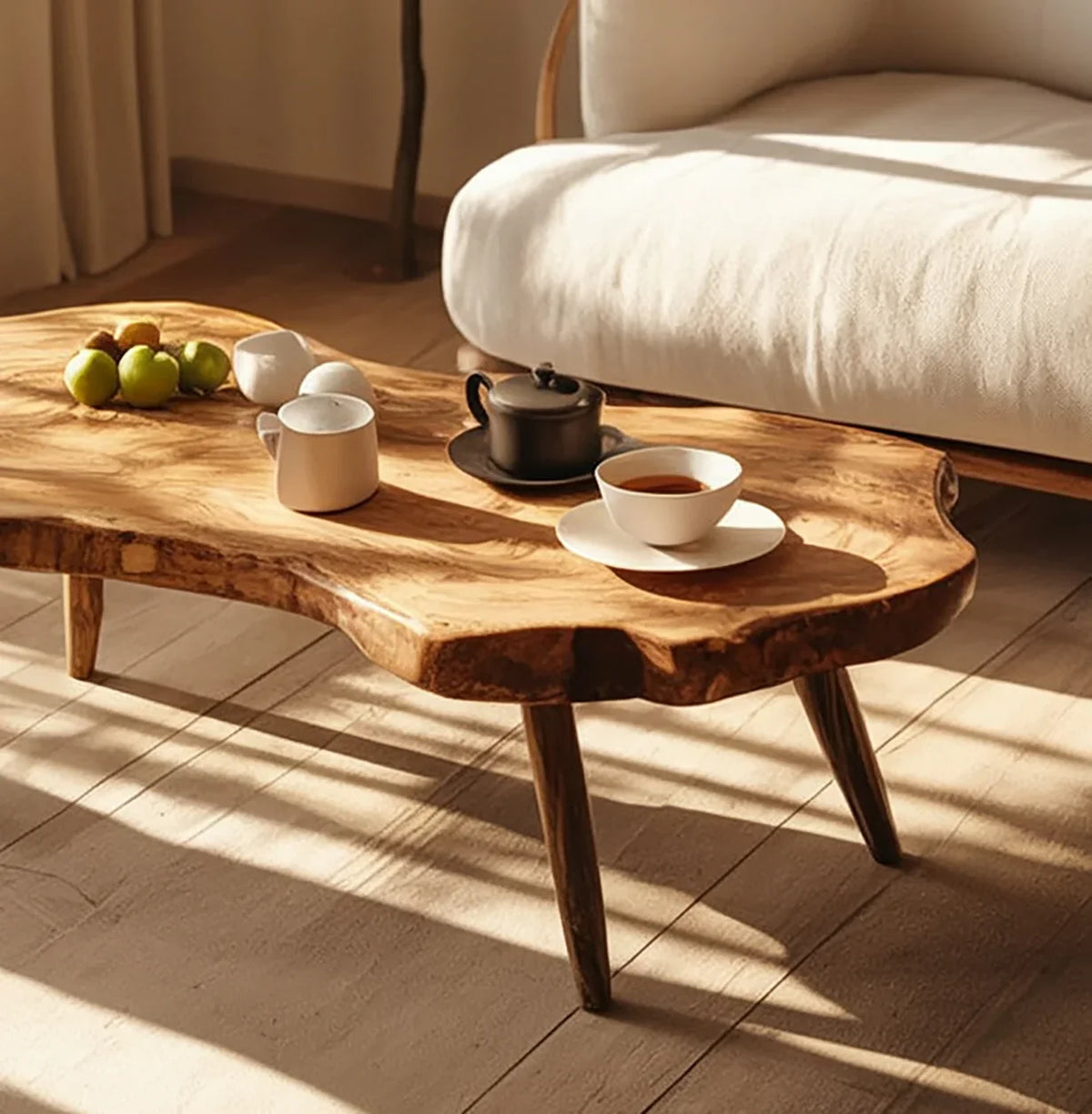 Solid wood live edge coffee table in sunlit room with tea set and apples