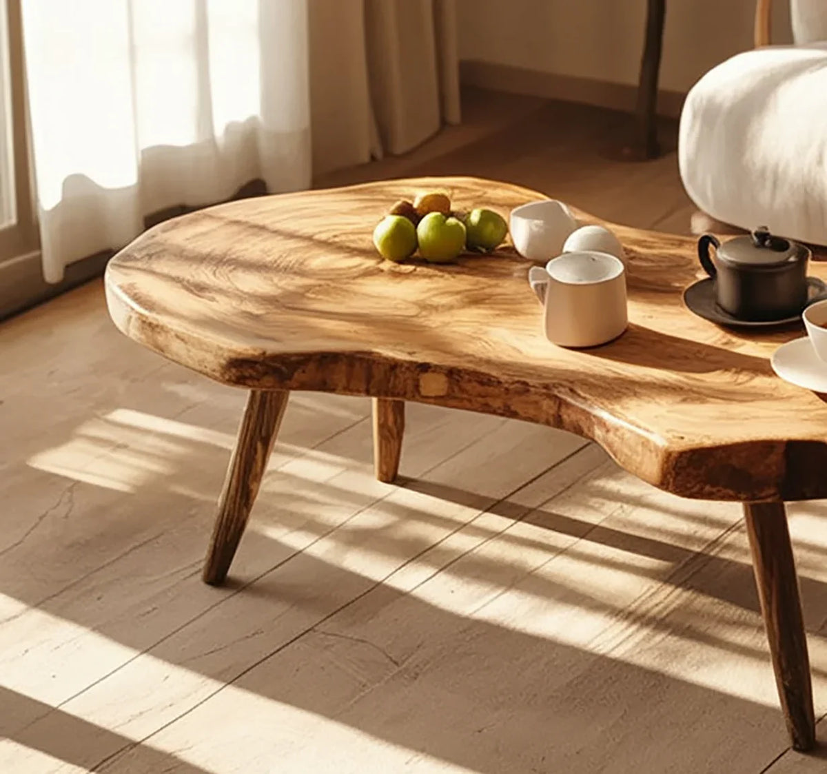 Live edge solid wood coffee table in sunlit living room with mugs, teapot, and green apples