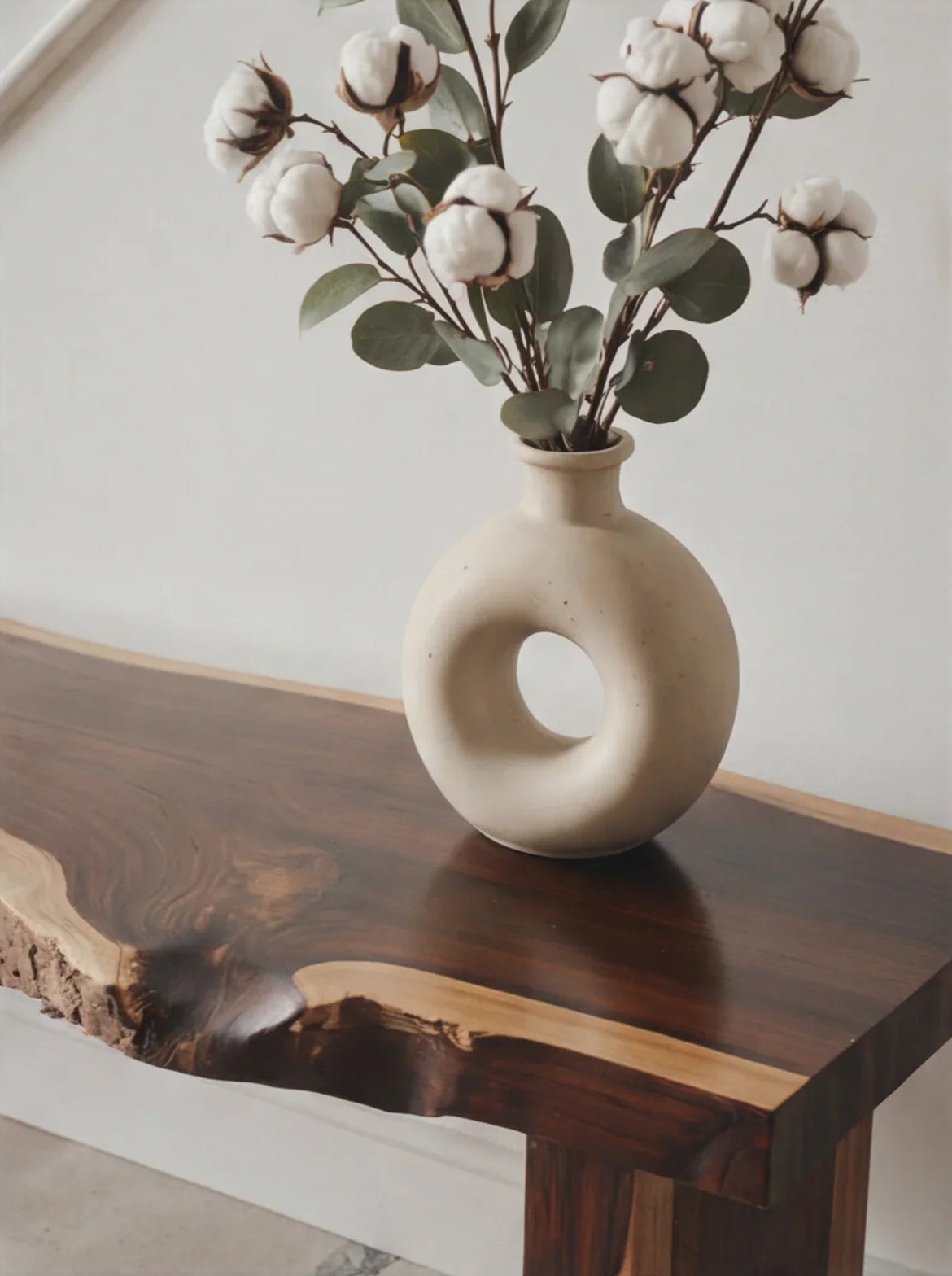 Modern ceramic vase with cotton stems on a live edge solid wood table