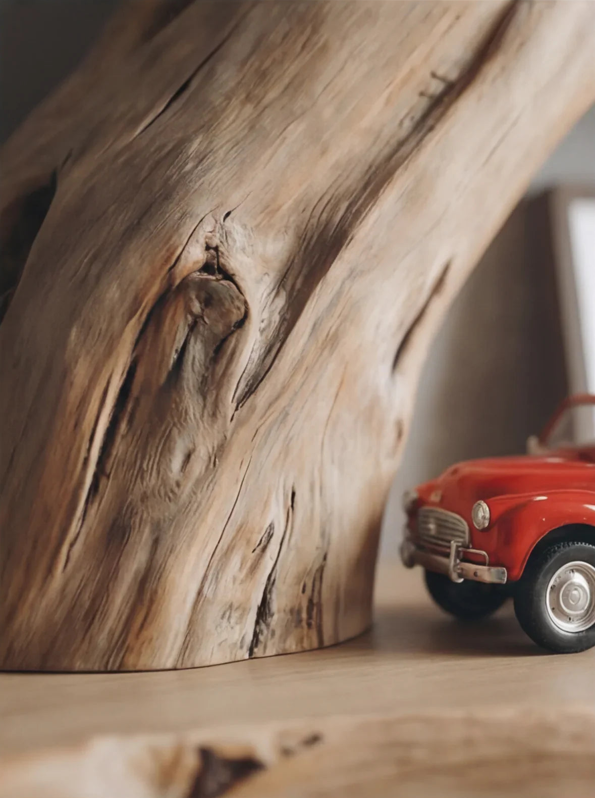 Close-up of solid wood furniture with natural live edge and a small red toy car beside it.