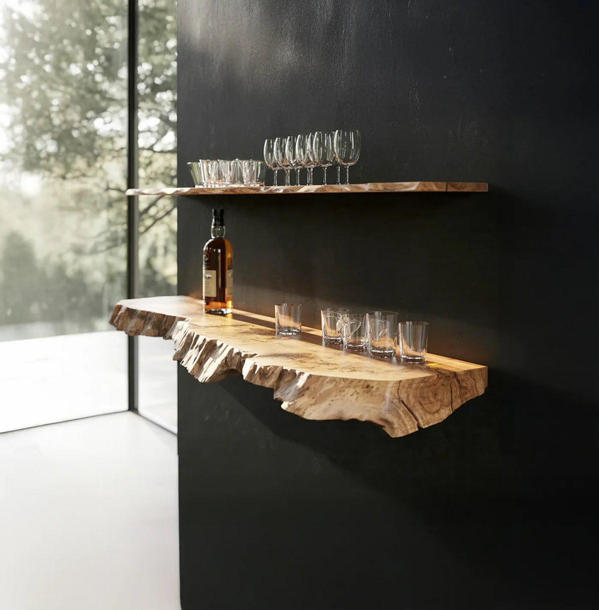 Live edge floating wooden shelves on a black wall with glassware and a bottle displayed.