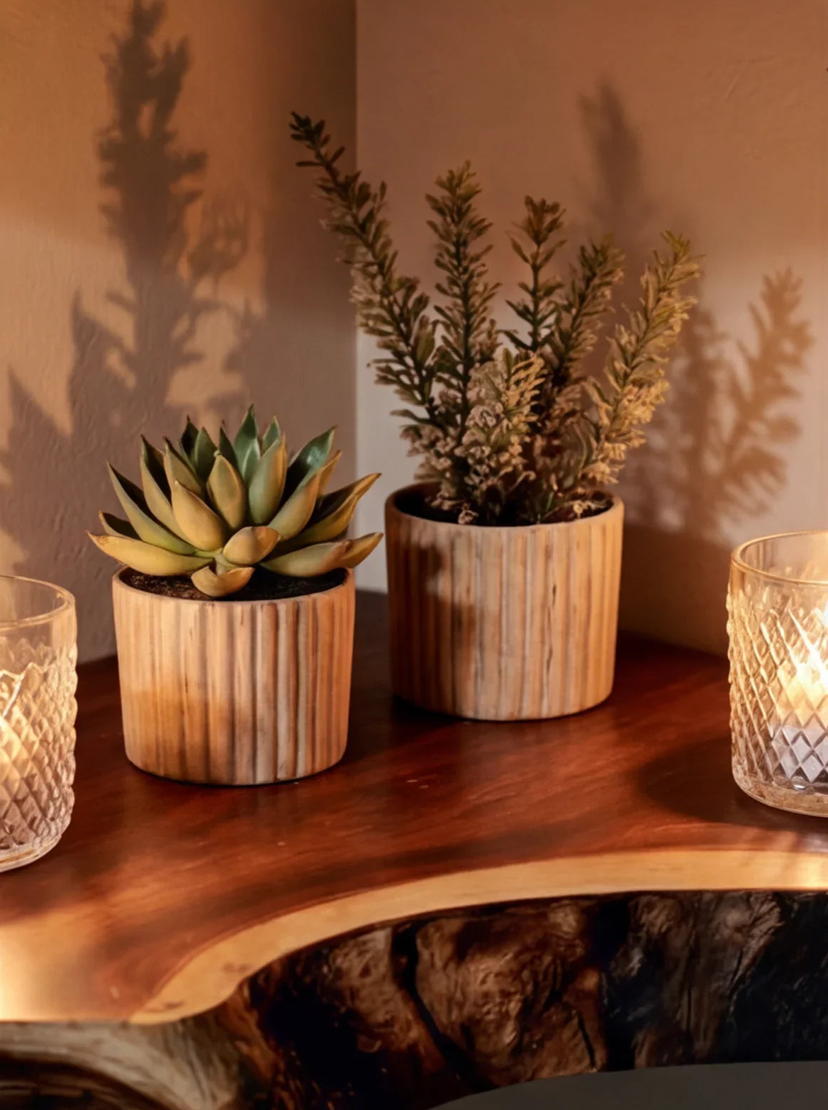 Succulent and evergreen plants in wooden pots on a live edge solid wood shelf with candles.