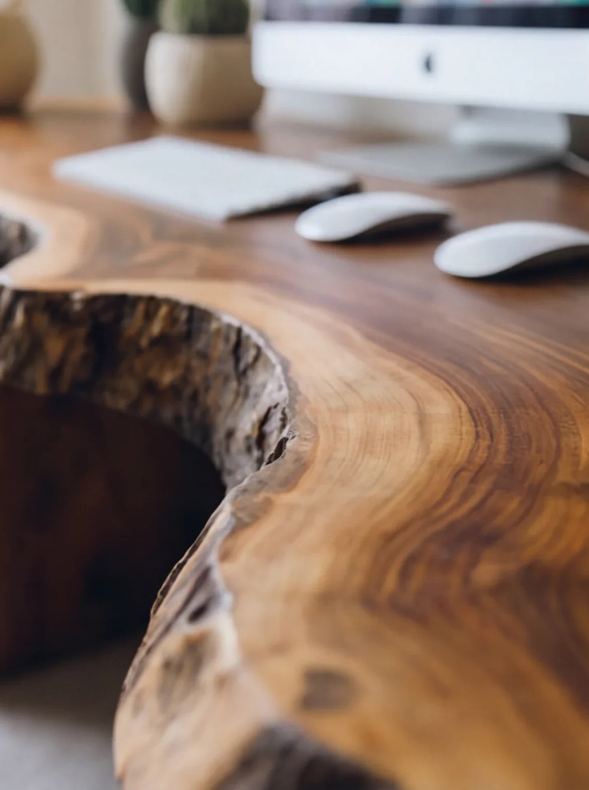 Solid wood live edge desk with natural grain, set in a modern workspace with computer accessories
