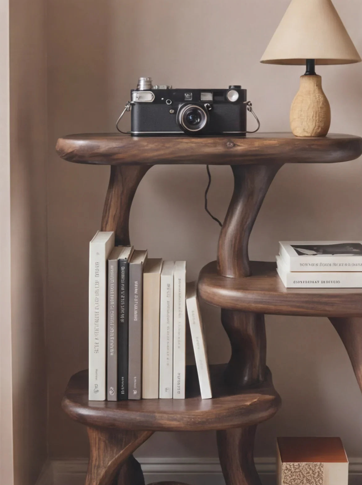 Solid wood live edge bookshelf with books, vintage camera, and small lamp