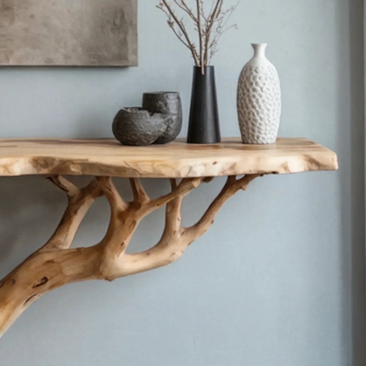 Live edge wood console table with branch base, decorated with modern vases.