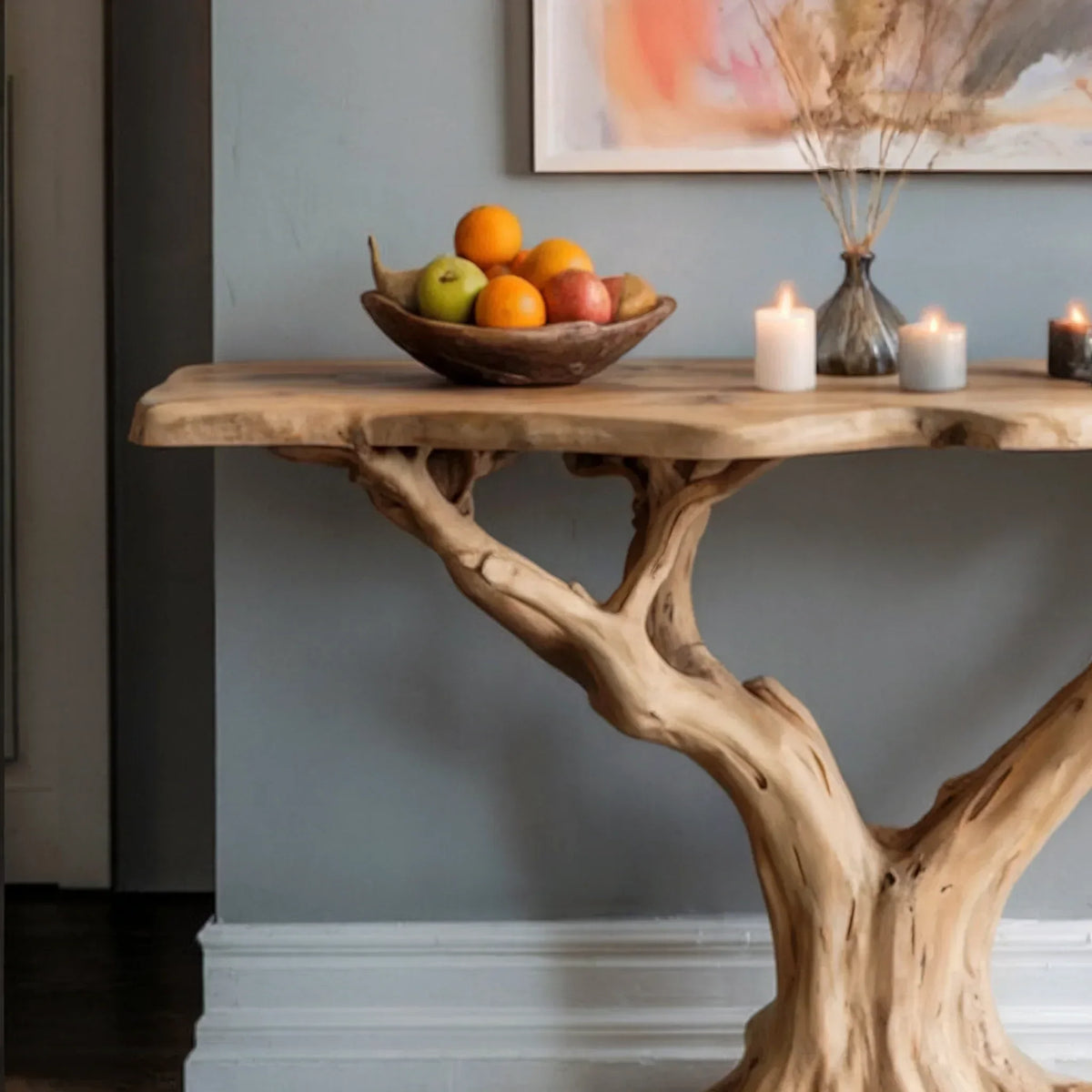 Live edge solid wood console table with tree branch base, fruit bowl, candles, and vase