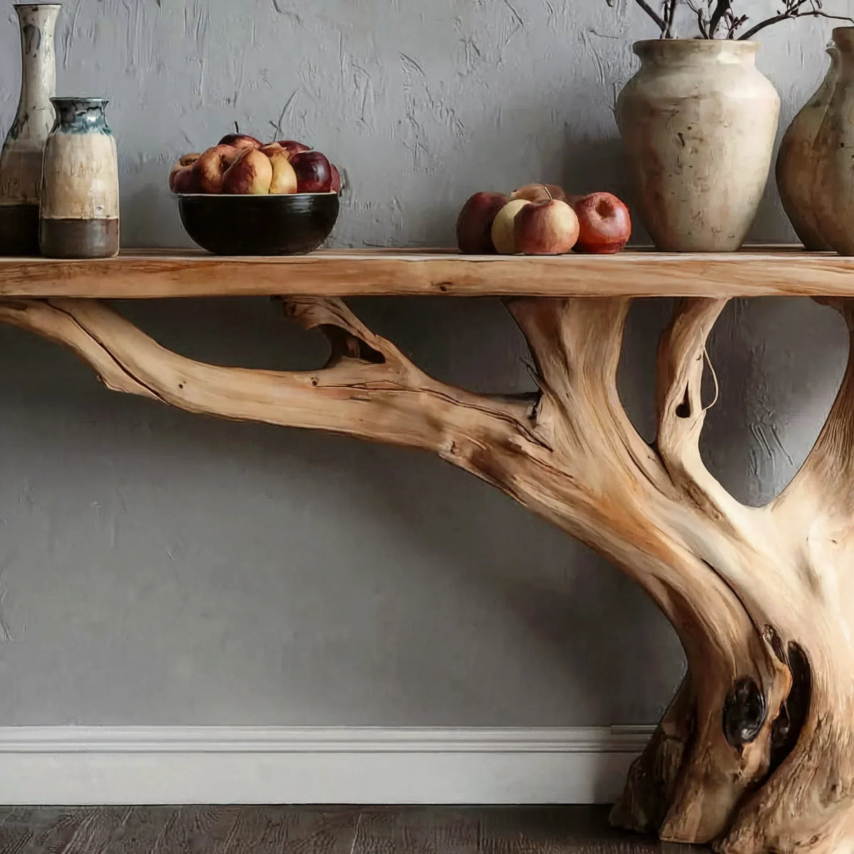 Live edge wooden console table with natural branch base, fruit bowl, pottery vases on top.