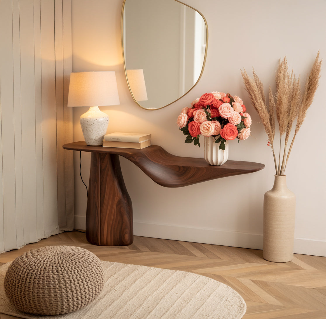 Solid wood live edge console table with lamp, books, and pink rose bouquet in modern entryway.