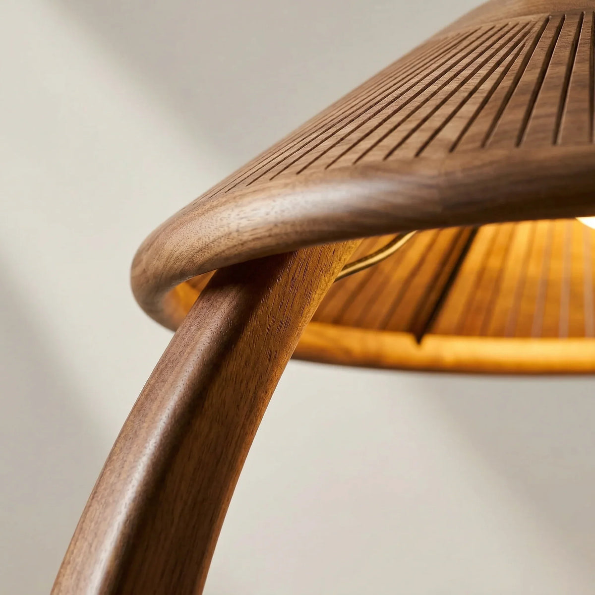 Close-up of a solid wood floor lamp with a slatted mushroom-shaped shade and curved stem