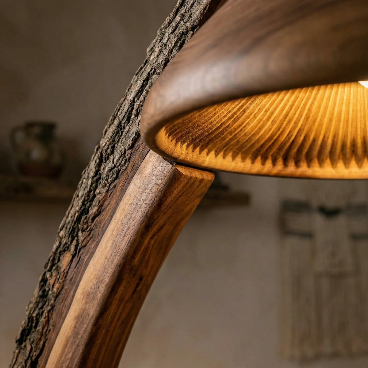 Close-up of a rustic mushroom arc floor lamp with a bark-on wooden stem and carved wood shade.