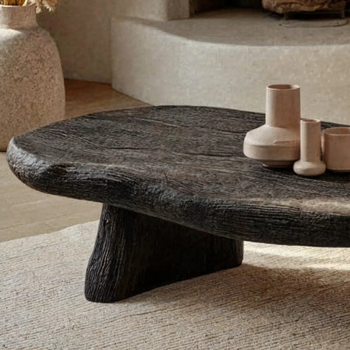 Close-up of a dark charcoal live edge wood coffee table with vases in a modern living room