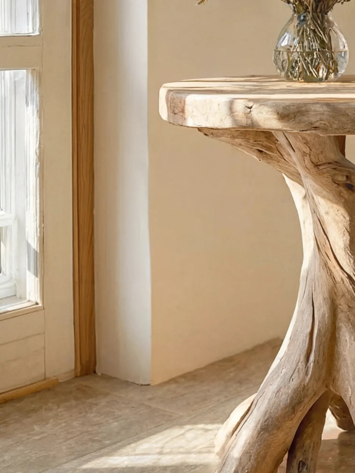 Close-up of a rustic live edge driftwood table with natural wood grain in sunlight.